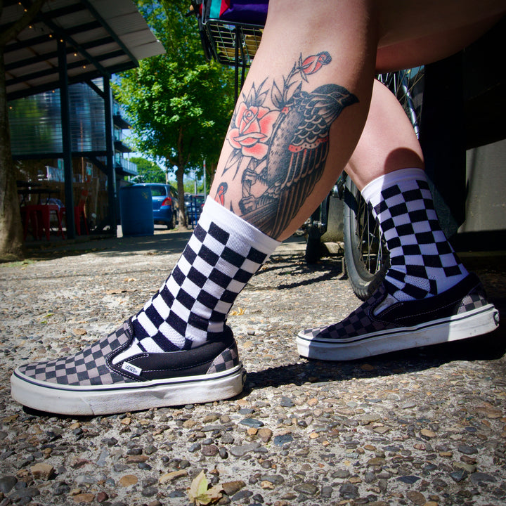 The SUPER TUFF Check Yourself Socks feature a bold checkerboard pattern, adding a rebellious flair to your athletic wear. Crafted for durability and comfort, these socks are perfect for activities like running, cycling, or hitting the gym. Made in the USA with recycled fibers, they combine style, performance, and sustainability