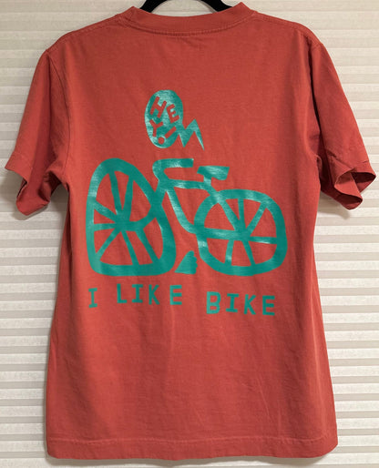 We are obsessed with this shirt. The mineral red is the perfect background for the I LIKE BIKE graphic. Let everyone know you LIKE BIKES without saying a word.

Fancy pics in the way. We just could not wait to put the shirt on the site.
Mineral red shirt with the text "I LIKE BIKE" and an image of the bike.