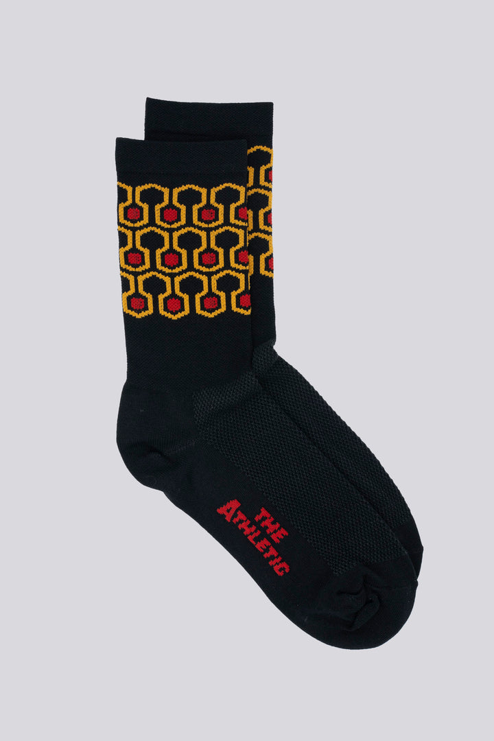 The Redrum Socks are inspired by the iconic carpet design at the Stanley Hotel in The Shining. These black socks feature a hexagon pattern and a 6" cuff, making them perfect for running, hiking, cycling, or the gym. Made in the USA from recycled fibers, they combine style, performance, and sustainability.