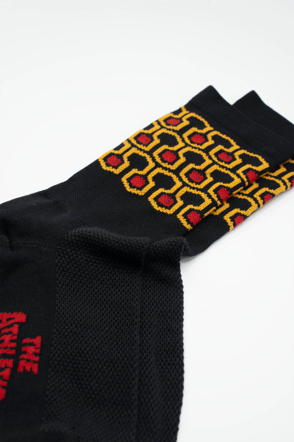 The Redrum Socks are inspired by the iconic carpet design at the Stanley Hotel in The Shining. These black socks feature a hexagon pattern and a 6" cuff, making them perfect for running, hiking, cycling, or the gym. Made in the USA from recycled fibers, they combine style, performance, and sustainability.