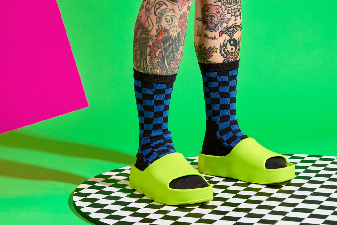 The SUPER TUFF Check Yourself Socks feature a bold checkerboard pattern, adding a rebellious flair to your athletic wear. Crafted for durability and comfort, these socks are perfect for activities like running, cycling, or hitting the gym. Made in the USA with recycled fibers, they combine style, performance, and sustainability