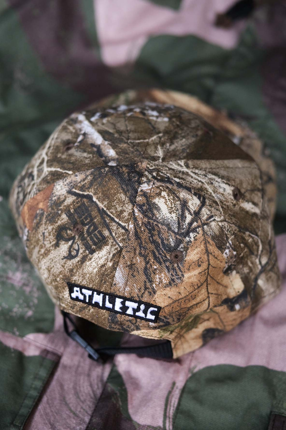 The Mid South Bootleg Camo Hat, a collaboration between The Athletic Community and Kyle Kelley, features a soft, regular-length bill and no top button, ensuring comfort under a helmet. Its unique camo pattern varies slightly with each hat, adding individuality to your gear. Crafted in the USA, this hat is perfect for everyday wear and is easily packable for on-the-go adventures