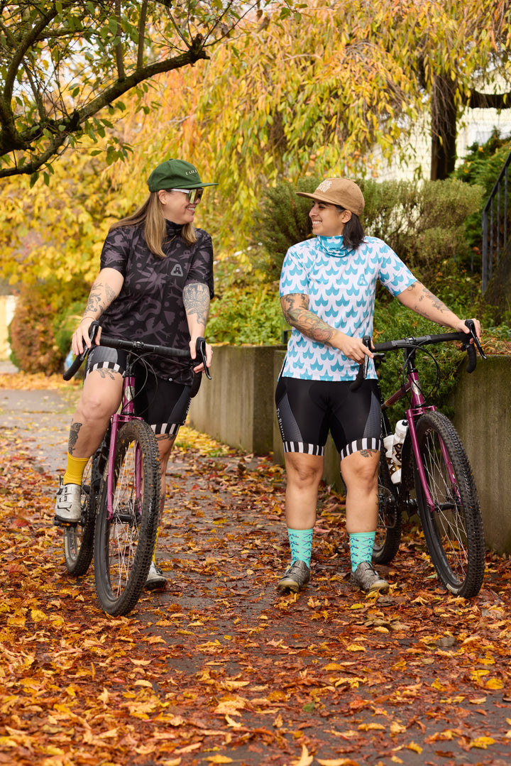 The Women's Duo-Tone Cargo Bibs are high-performance cycling bibs crafted from EIT Eco X-Mix fabric, featuring two side and rear pockets for added storage. Designed by Young Jerks and made in California from Italian fabrics by Endo Customs, these bibs offer both style and functionality for cyclists.