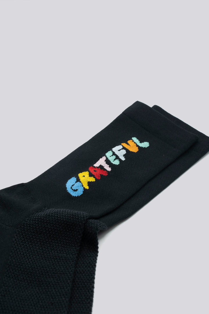 The Grateful Socks are designed to inspire positivity and gratitude, featuring the word "Grateful" prominently displayed. Ideal for cycling, running, and cross-training, these socks combine style and performance. Available in oatmeal with blue text and blue with white text. Made in the USA with recycled fibers, they offer both durability and sustainability