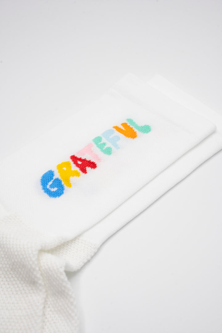 The Grateful Socks are designed to inspire positivity and gratitude, featuring the word "Grateful" prominently displayed. Ideal for cycling, running, and cross-training, these socks combine style and performance. Available in oatmeal with blue text and blue with white text. Made in the USA with recycled fibers, they offer both durability and sustainability