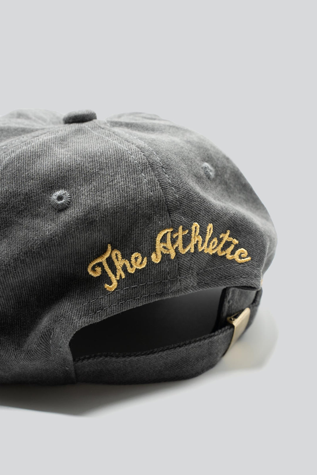 Gray dad hat with a horned cow and a sun embroidered in gold and red and "The Athletic" embroidered in the back