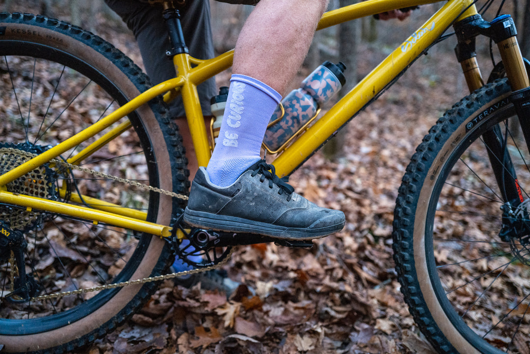 Lavender socks with "Be Curious" on either side of the sock for running and cycling