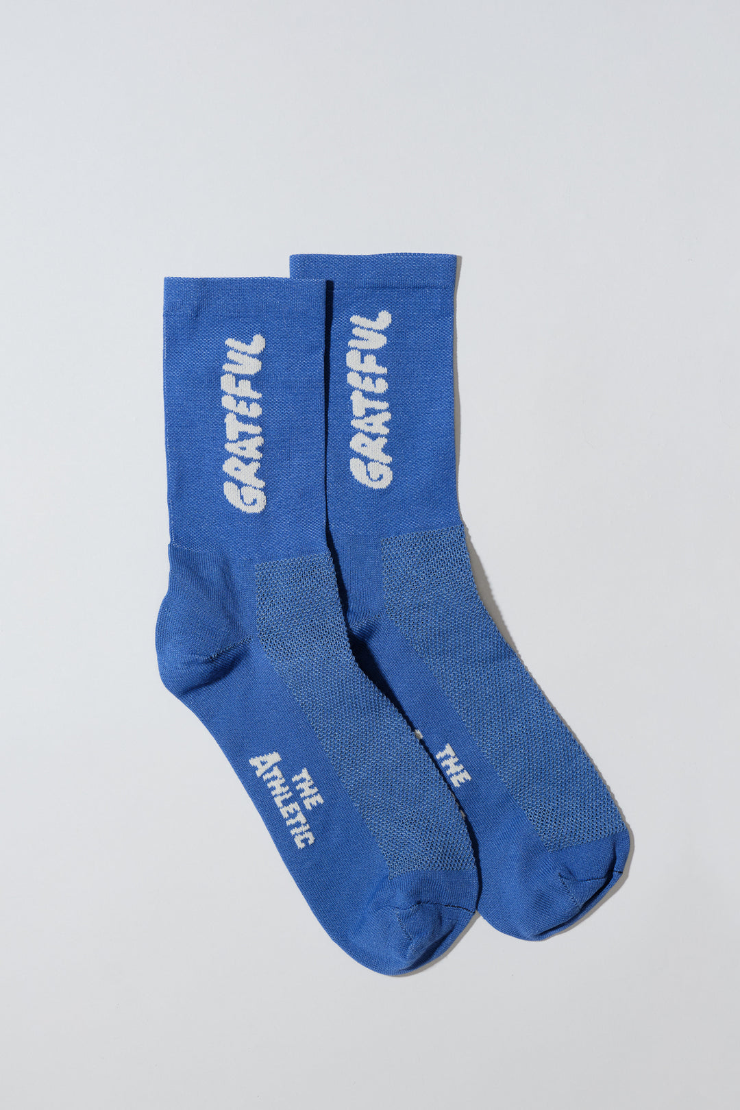 The Grateful Socks are designed to inspire positivity and gratitude, featuring the word "Grateful" prominently displayed. Ideal for cycling, running, and cross-training, these socks combine style and performance. Available in oatmeal with blue text and blue with white text. Made in the USA with recycled fibers, they offer both durability and sustainability