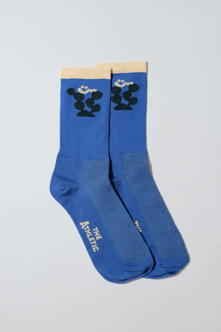 The Happy Cactus Socks, designed by artist Will Bryant, feature a playful cactus and smiley face design. Made in the USA with love, these socks are perfect for adding a touch of fun to your athletic wear. Ideal for cycling, running, and casual wear, they combine style and performance