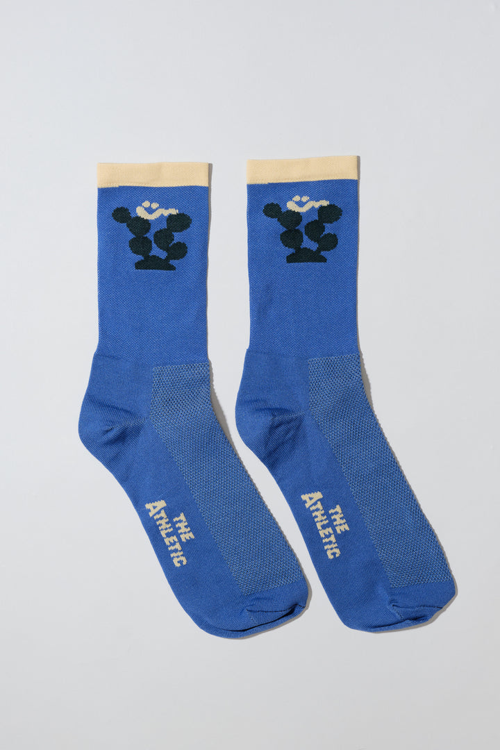 The Happy Cactus Socks, designed by artist Will Bryant, feature a playful cactus and smiley face design. Made in the USA with love, these socks are perfect for adding a touch of fun to your athletic wear. Ideal for cycling, running, and casual wear, they combine style and performance