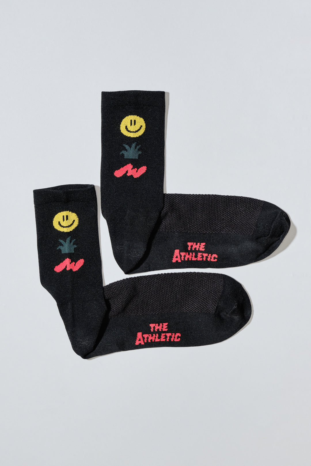 The Happy Trio Socks feature a playful design with a smiley face, cactus, and squiggle, available in off-white and black color options. Ideal for cycling, running, and cross-training, these socks combine style and performance. Made in the USA with love, they offer both durability and comfort