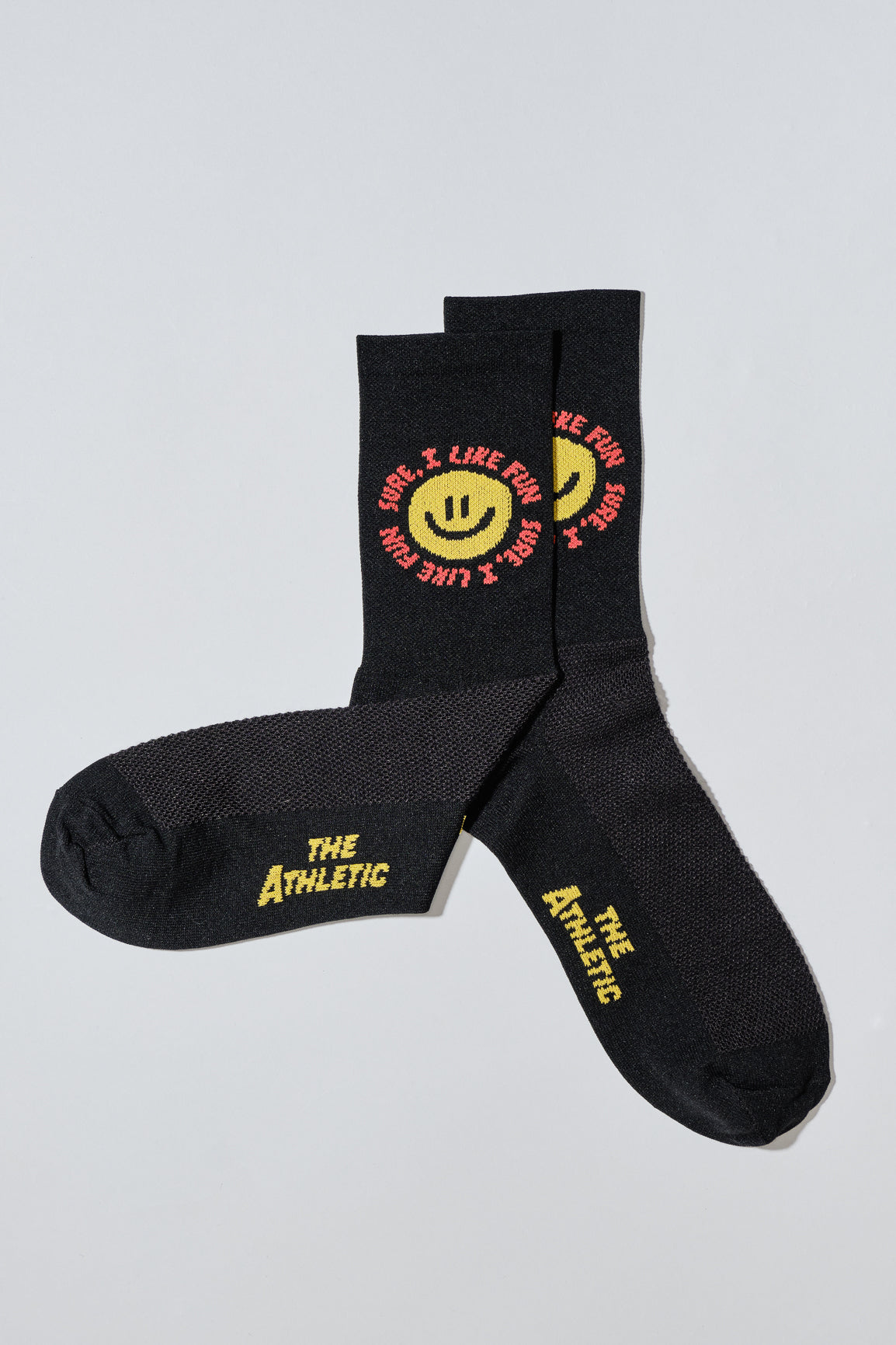 Smiley face socks with "Sure, I like fun" caption. Socks are black.